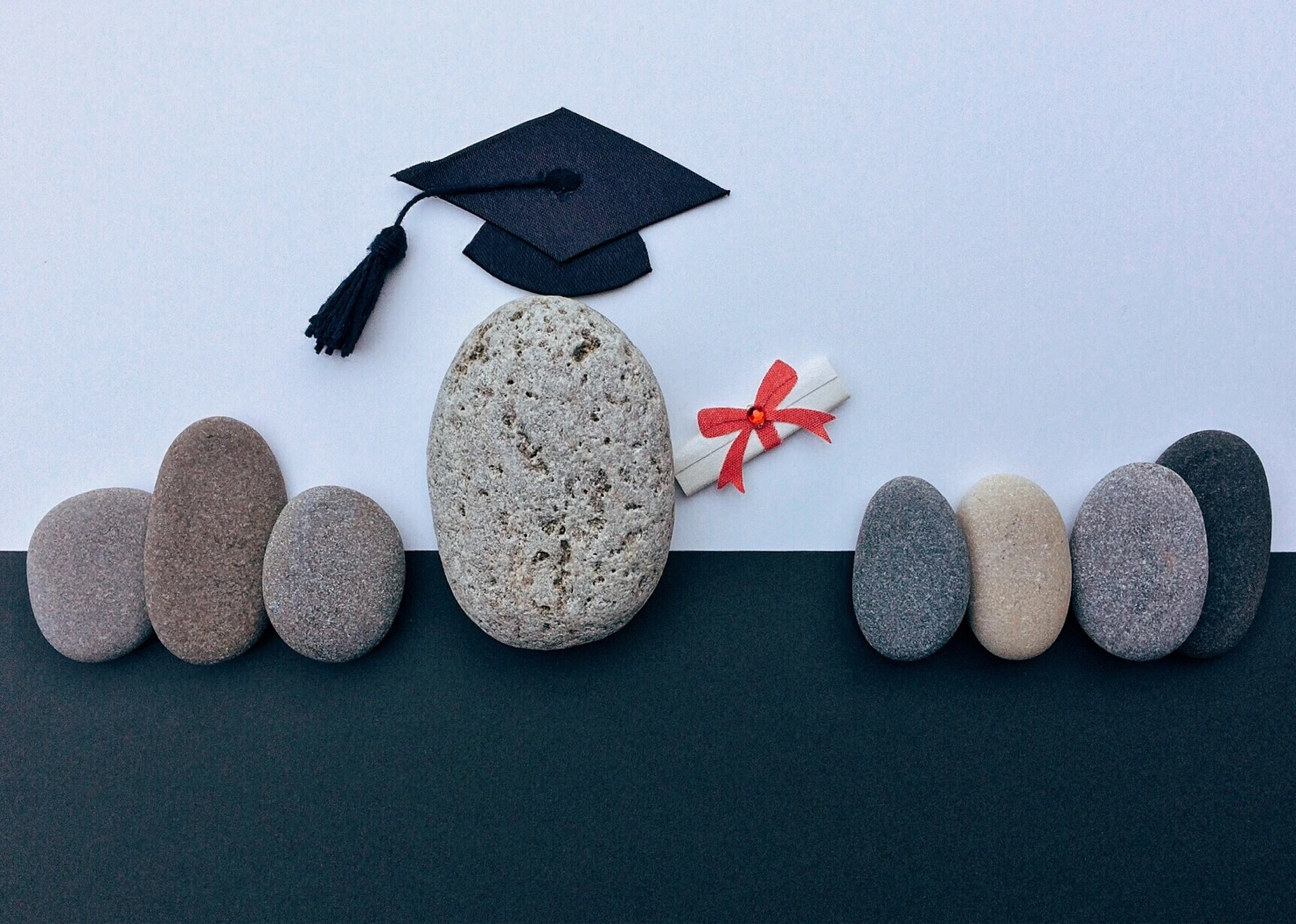 Piedras planas simulando alumnos con un diploma y birrete