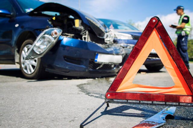 Coche accidentado y triangulo de aviso en la via