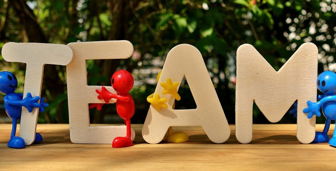 Muchequitos de colores, sonriendo y abrazados a las letras de la palabra team